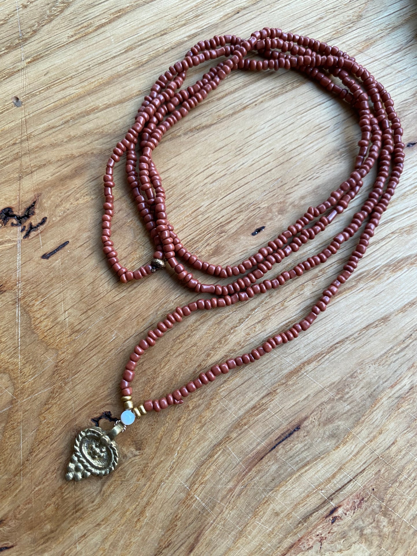 Dunne ketting gemaakt van bruine glazen rocailles, met indiase hanger